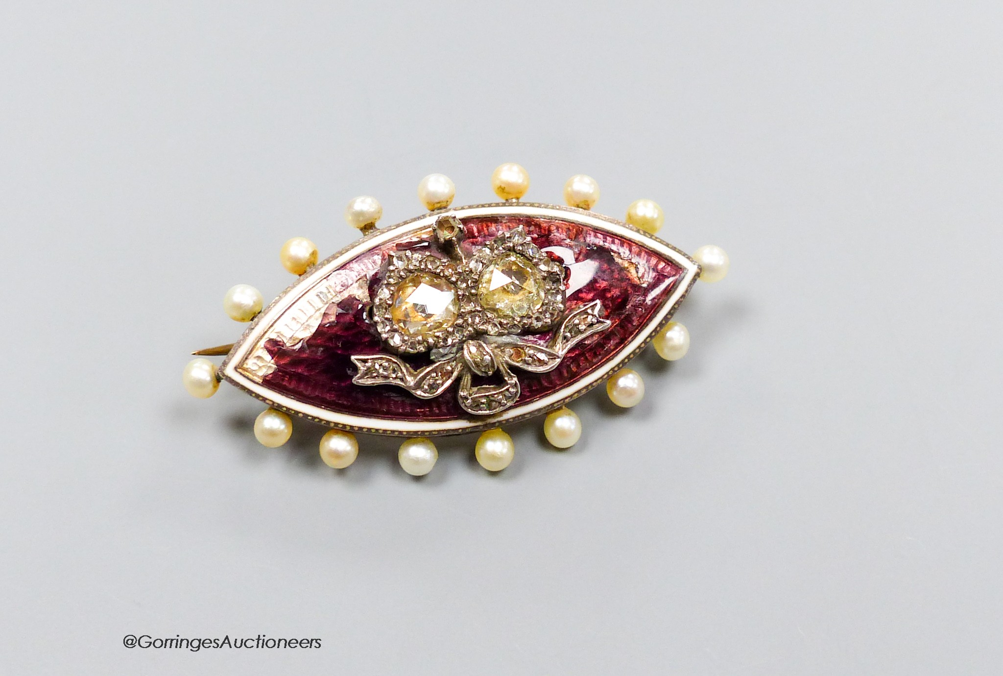 An Edwardian yellow metal, diamond, enamel and seed pearl set navette shaped 'twin hearts' brooch, 40mm, gross 8.7 grams (a.f.).